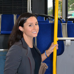 A young woman in a suit holding the safety pole on a DC area bus