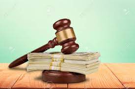 A gavel with a stack of dollar bills beneath it